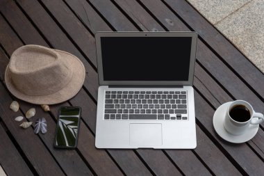 Dizüstü bilgisayar ve akıllı telefon ile kahve fincanı ve ahşap üzerine şapka. laptop ya da defter ve havuz başında şapka. 