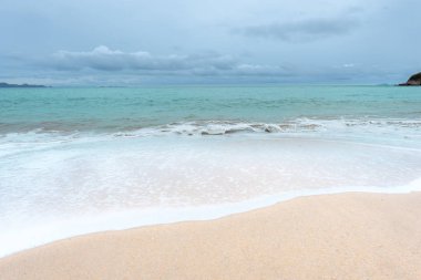 Yumuşak dalgalar üzerinde kum plaj. Beyaz kabarcıklar sahilde okyanus dalgaları seashore tarafından yaratılmıştır. Akış dalga ile tropikal plaj.