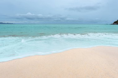 Yumuşak dalgalar üzerinde kum plaj. Beyaz kabarcıklar sahilde okyanus dalgaları seashore tarafından yaratılmıştır. Akış dalga ile tropikal plaj.
