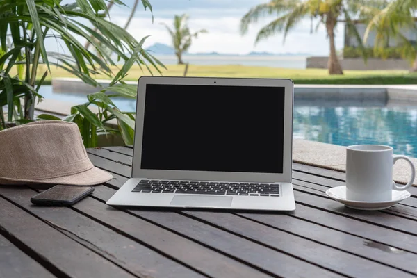 Dizüstü bilgisayar ve akıllı telefon ile kahve fincanı ve ahşap üzerine şapka. laptop ya da defter ve havuz başında şapka. 