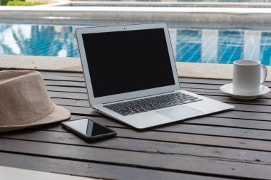 Dizüstü bilgisayar ve akıllı telefon ile kahve fincanı ve ahşap üzerine şapka. laptop ya da defter ve havuz başında şapka. 