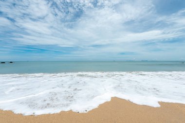 Yumuşak dalgalar üzerinde kum plaj. Beyaz kabarcıklar sahilde okyanus dalgaları seashore tarafından yaratılmıştır. Akış dalga ile tropikal plaj.