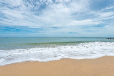 Yumuşak dalgalar üzerinde kum plaj. Beyaz kabarcıklar sahilde okyanus dalgaları seashore tarafından yaratılmıştır. Akış dalga ile tropikal plaj.