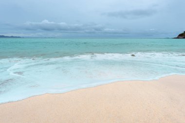 Yumuşak dalgalar üzerinde kum plaj. Beyaz kabarcıklar sahilde okyanus dalgaları seashore tarafından yaratılmıştır. Akış dalga ile tropikal plaj.