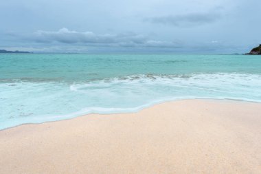 Yumuşak dalgalar üzerinde kum plaj. Beyaz kabarcıklar sahilde okyanus dalgaları seashore tarafından yaratılmıştır. Akış dalga ile tropikal plaj.