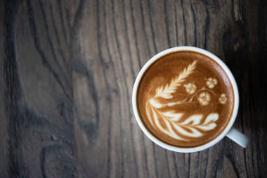 Beyaz kahve fincanı kalp şekli latte sanat köpük üzerinde siyah ahşap masa pencere yakınındaki ile kapatın. Üstten görünüm latte sanat kahve Kupası.