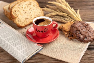 Sıcak kahve fincanı ve ahşap arka plan üzerinde pişmiş kahvaltı. Lezzetli kurabiyeleri, tahta arka plan ile lezzetli kahve fincan. Americano kahve ve kurabiye ile ekmek. Kırmızı kahve fincanı.