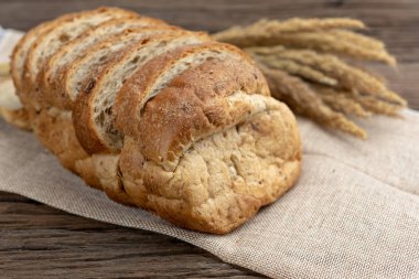 Ayçiçeği tohumu ve çuval üzerinde susam ile dilimlenmiş ekmek. Taze ev yapımı kepekli ekmek ahşap tablo.