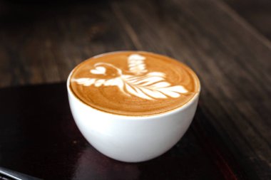 Cafe ahşap masa üzerinde beyaz kahve fincanı. Latte sanat kahve Kupası.