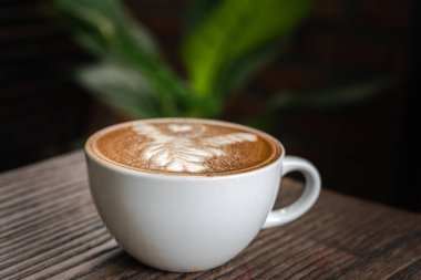 Cafe ahşap masa üzerinde beyaz kahve fincanı. Latte sanat kahve Kupası.