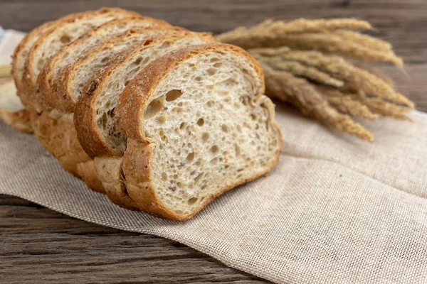 Ayçiçeği tohumu ve çuval üzerinde susam ile dilimlenmiş ekmek. Taze ev yapımı kepekli ekmek ahşap tablo.