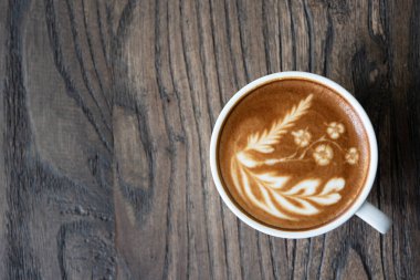 Beyaz kahve fincanı kalp şekli latte sanat köpük üzerinde siyah ahşap masa pencere yakınındaki ile kapatın. Üstten görünüm latte sanat kahve Kupası.