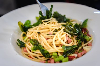 Spagetti bacon ve fesleğen ile baharatlı biber arka plan üzerinde beyaz tabak içinde kurumuş. Pastırma, parsel ve parmesan peynirli spagetti. Beyaz tabakta makarna Carbonara koyu arka plan üzerine parmesan ile.