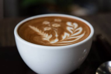 Cafe ahşap masa üzerinde beyaz kahve fincanı. Latte sanat kahve Kupası.
