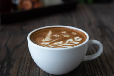 Cafe ahşap masa üzerinde beyaz kahve fincanı. Latte sanat kahve Kupası.