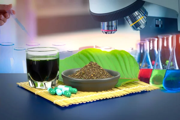 Toz ürün beyaz seramik kase ve su ile Mitragynina speciosa veya Kratom kratom yaprakları özler bırakır. Kratom yeşil kapsül ek. Laboratuvar cam ve Mitragyna specios renk sıvı ile çalışan bilim adamı