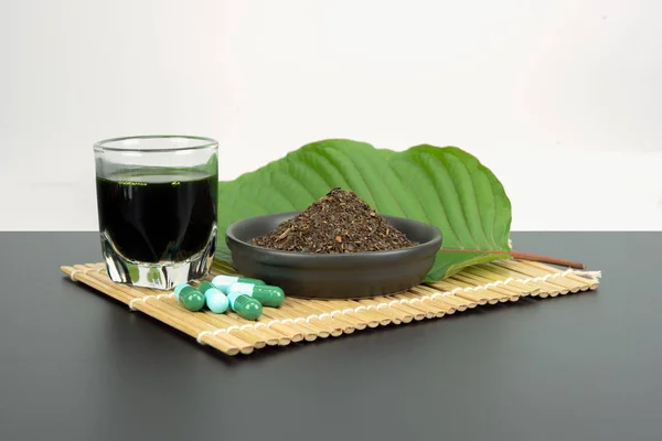 Toz ürün beyaz seramik kase ve su ile Mitragynina speciosa veya Kratom kratom yaprakları özler bırakır. Ek kratom yeşil kapsül. 