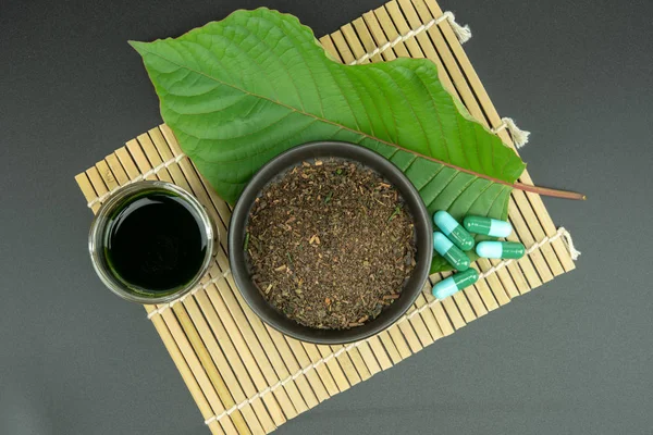 Toz ürün beyaz seramik kase ve su ile Mitragynina speciosa veya Kratom kratom yaprakları özler bırakır. Ek kratom yeşil kapsül. 