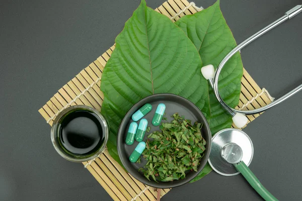 Toz ürün beyaz seramik kase ve su ile Mitragynina speciosa veya Kratom kratom yaprakları özler bırakır. Ek kratom yeşil kapsül. 