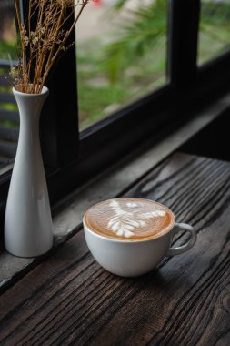 Cafe ahşap masa üzerinde beyaz kahve fincanı. Latte sanat kahve Kupası.