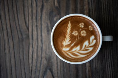 Beyaz kahve fincanı kalp şekli latte sanat köpük üzerinde siyah ahşap masa pencere yakınındaki ile kapatın. Üstten görünüm latte sanat kahve Kupası.