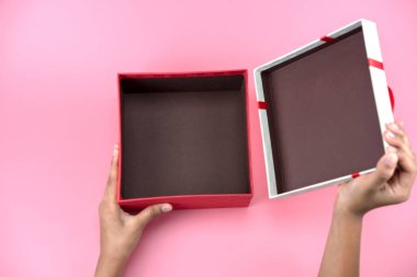 el ele tutuşur boş kırmızı ve beyaz hediye kutusu için tatil, Noel, pembe bir arka plan üzerinde teşekkür veren gün, Doğum günü. Kırmızı holding genç kadın eller hediye kutusu. 