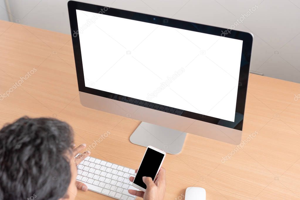 Office monitor computer, mouse on wooden table. computer and keyboard, mouse with blank screen. Digital business concept. Young man looking at empty computer screen, back view