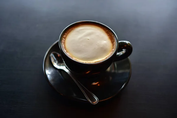 Coffee cup. A cup of coffee in a black cup on wooden background