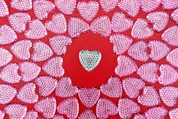 love symbol. Glitter hearts. Pink hearts on red background. Top view. Valentine\'s Day. Symbol of love. Copy space.