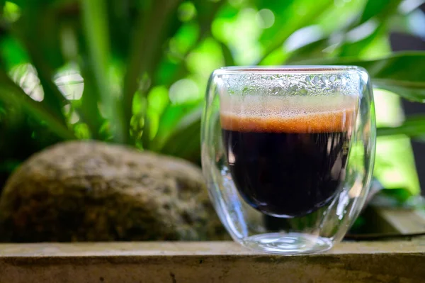 Cup of espresso on the table. glass beaker for shot-cocktail or coffee drinks. Close up of a glass of espresso. Hot coffee in a glass with double walls isolated on a white background.