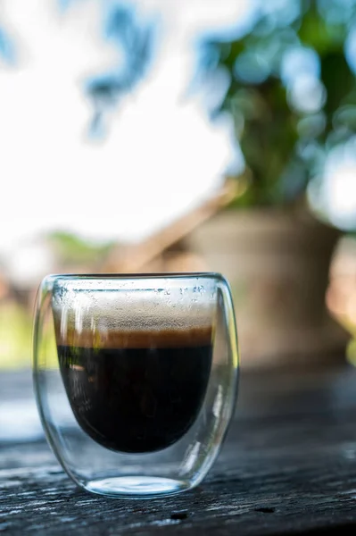 Cup of espresso on the table. glass beaker for shot-cocktail or coffee drinks. Close up of a glass of espresso. Hot coffee in a glass with double walls isolated on a white background.