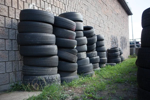 Caoutchouc industrie empilés pneus usagés contre le mur de brique — Photo