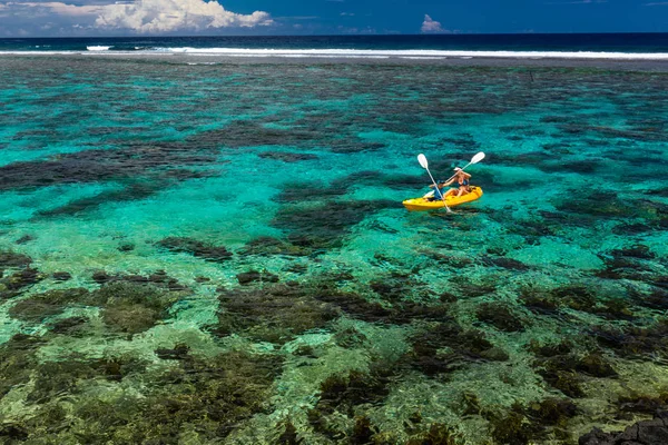 熱帯のサンゴ礁のラグーンにカヌーを漕ぐ女性と坊や — ストック写真
