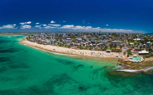 Aerial drone panoramic image of ocean waves on a busy Kings beach, Caloundra, Queensland, Australia