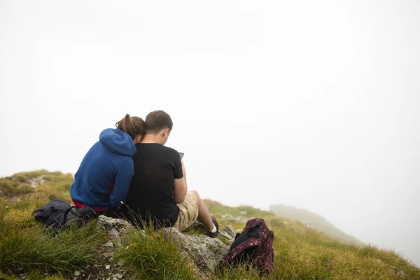 山の上に座るし 景色を若い人たちの美しいカップル — ストック写真