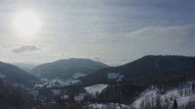 Binalar ile köy karla kaplı. Bulutların arasında havadan görünümü