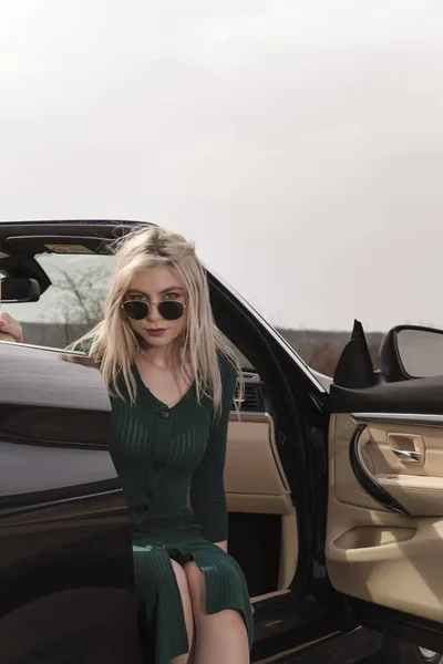 Atractiva joven posando apoyada en un coche descapotable — Foto de Stock