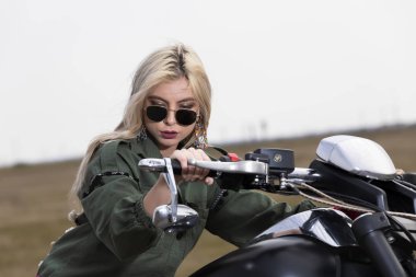 Güzel bir genç kadın siyah ve krom motosiklet üzerinde oturuyordu