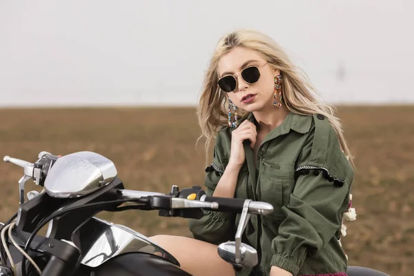 Una bella giovane donna seduta su una moto nera e cromata — Foto Stock