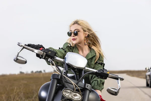 Een mooie jonge vrouw zitten op een motor zwart en chroom — Stockfoto