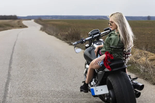 Красивая молодая женщина, сидящая на черно-хромовом мотоцикле — стоковое фото