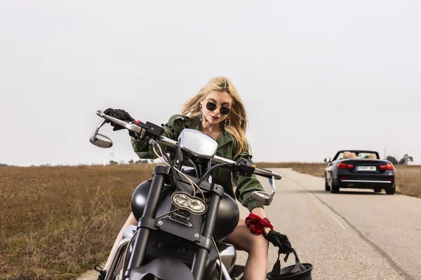 Красивая молодая женщина, сидящая на черно-хромовом мотоцикле — стоковое фото