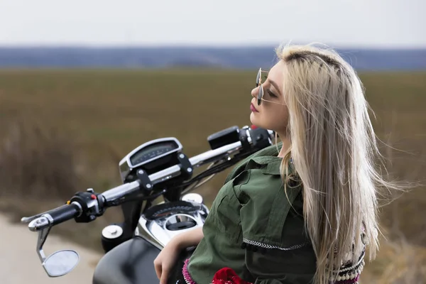 Une belle jeune femme assise sur une moto noire et chromée — Photo