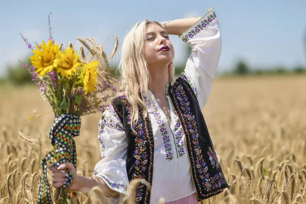 Vacker flicka i traditionell kostym i ett vetefält — Stockfoto