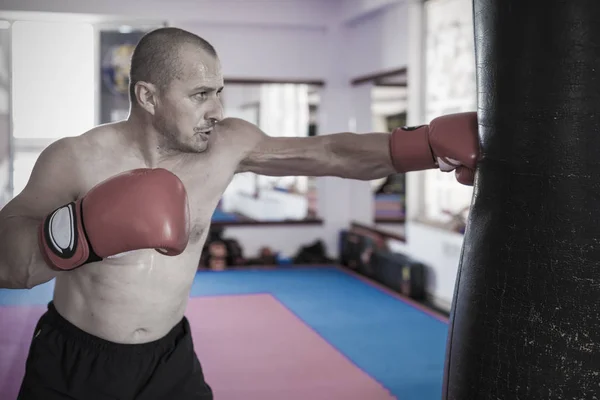 Muay thai lutador batendo o saco pesado no ginásio — Fotografia de Stock