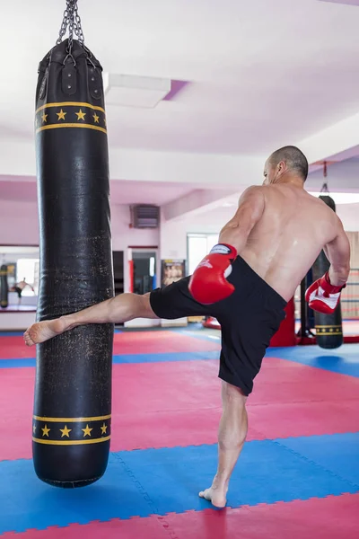 Muay thai luchador golpear la bolsa pesada en el gimnasio —  Fotos de Stock