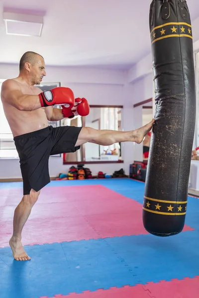 Muay thai luchador golpear la bolsa pesada en el gimnasio — Foto de Stock