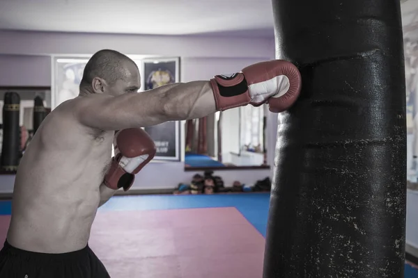 Muay thai bojovník bít boxovací pytel v tělocvičně — Stock fotografie