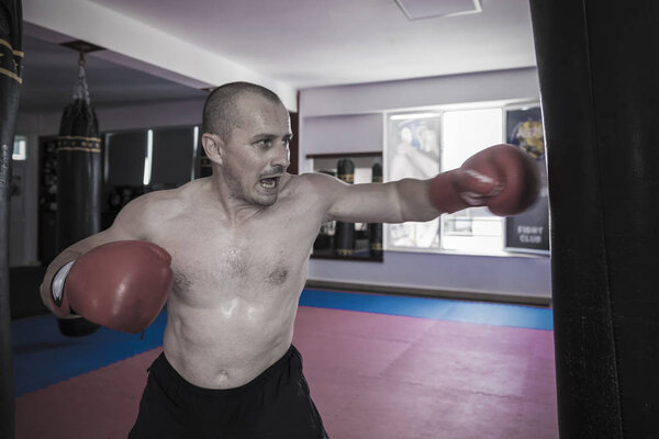 Muay thai fighter hitting the heavy bag in the gym