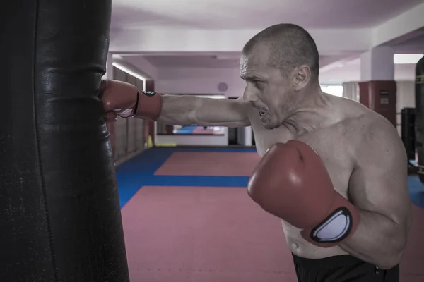 Muay thai luchador golpear la bolsa pesada en el gimnasio — Foto de Stock